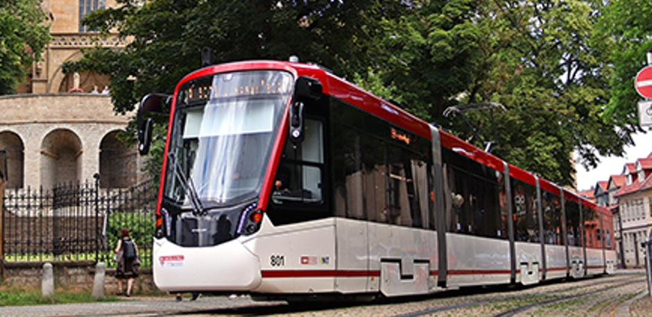 Moderne Straßenbahn in roter und weißer Lackierung vor Dom.