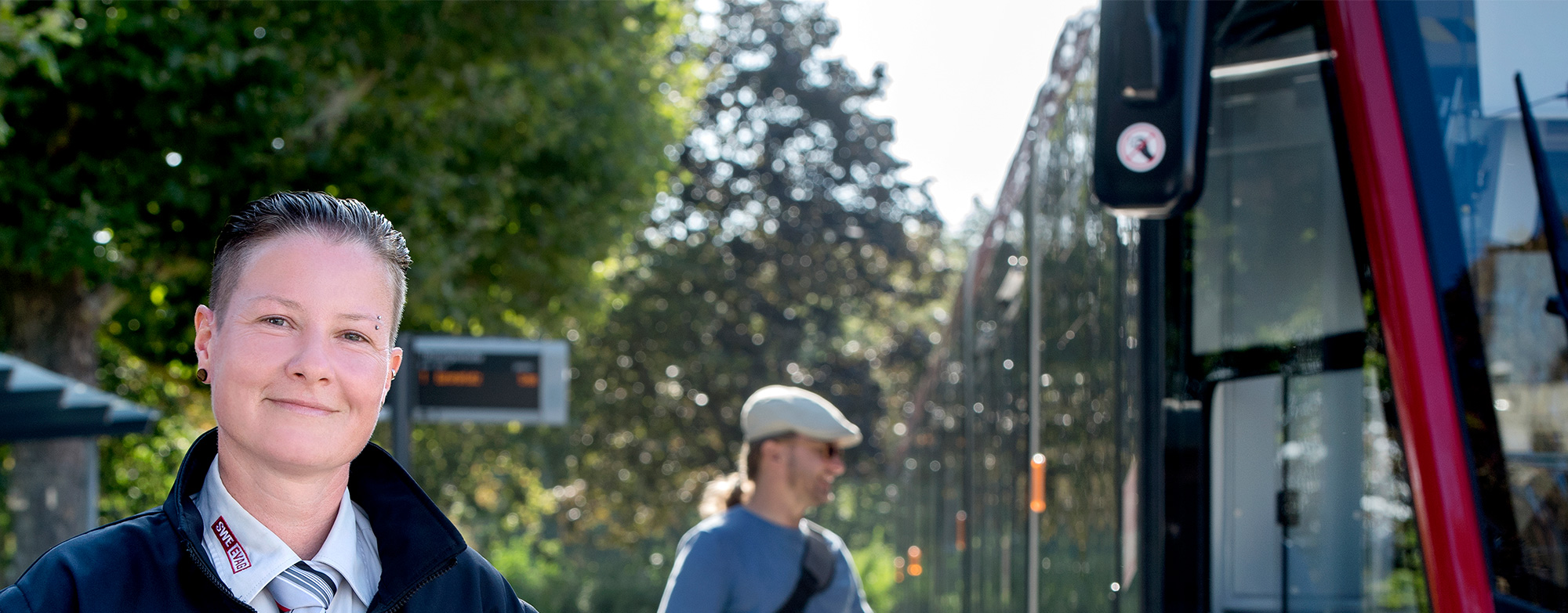 Busfahrerin l&auml;chelt einsteigenden Fahrgast an.