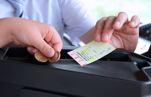 Kinderhand legt Geld an der Kasse im Bus ab. Hand des Busfahrers hält Ticket in der Hand