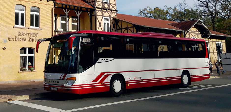 Reisebus mit wei&szlig;er und wei&szlig;er Lackierung vor dem Gasthof Schloss Hubertus.