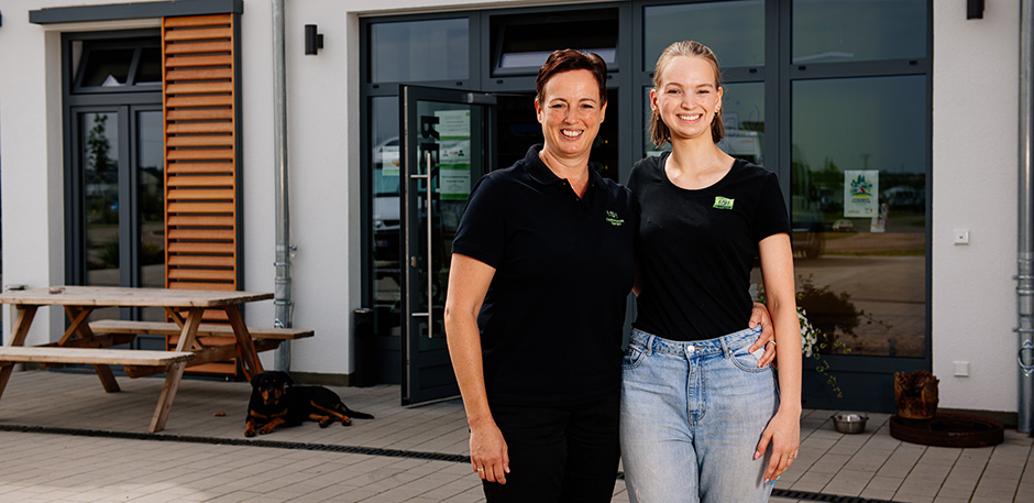 Zwei Frauen stehen vor dem Empfangsgeb&auml;ude eines Campingplatzes.