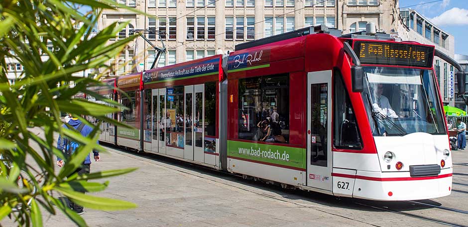 Moderne Straßenbahn in roter und weißer Lackierung auf dem Anger. Im Hintergrund das Kaufhaus Anger 1.
