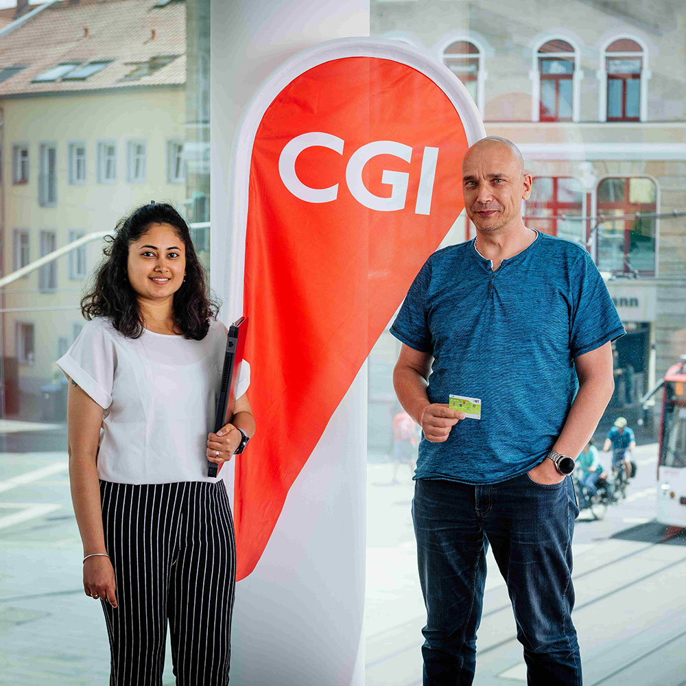 Mann und Frau. Zwischen ihnen ein Aufsteller, auf dem "CGI" steht. Der Mann h&auml;lt eine gr&uuml;ne Chipkarte in der Hand.