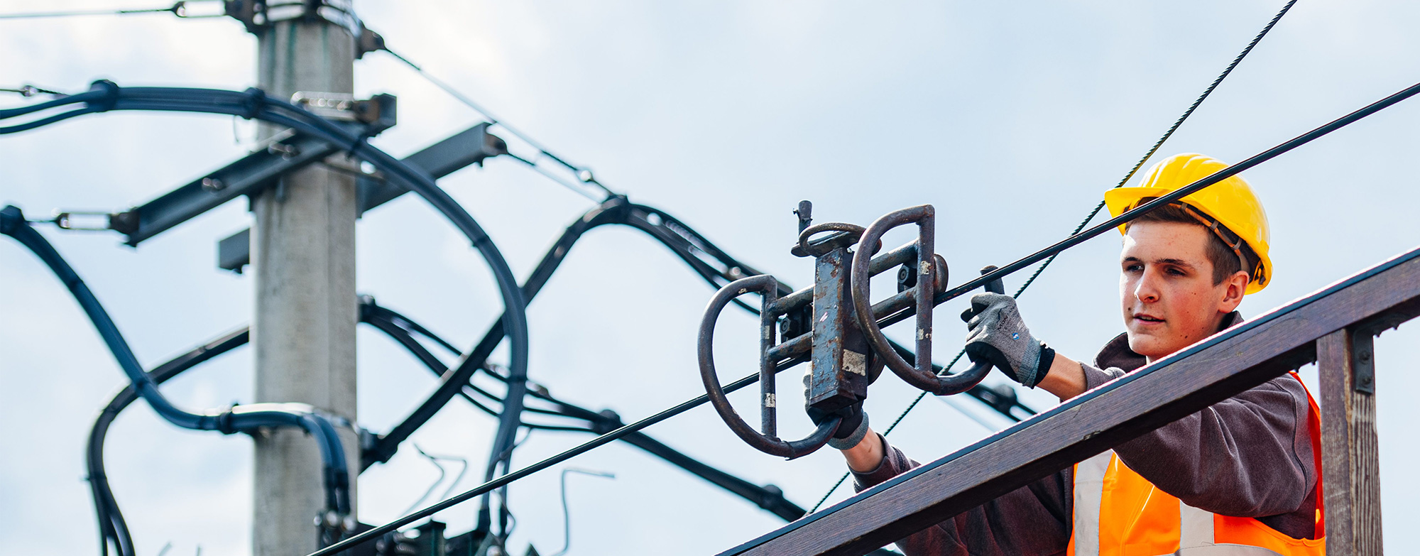 Junger Mann in Schutzausr&uuml;stung an der Oberleitung.