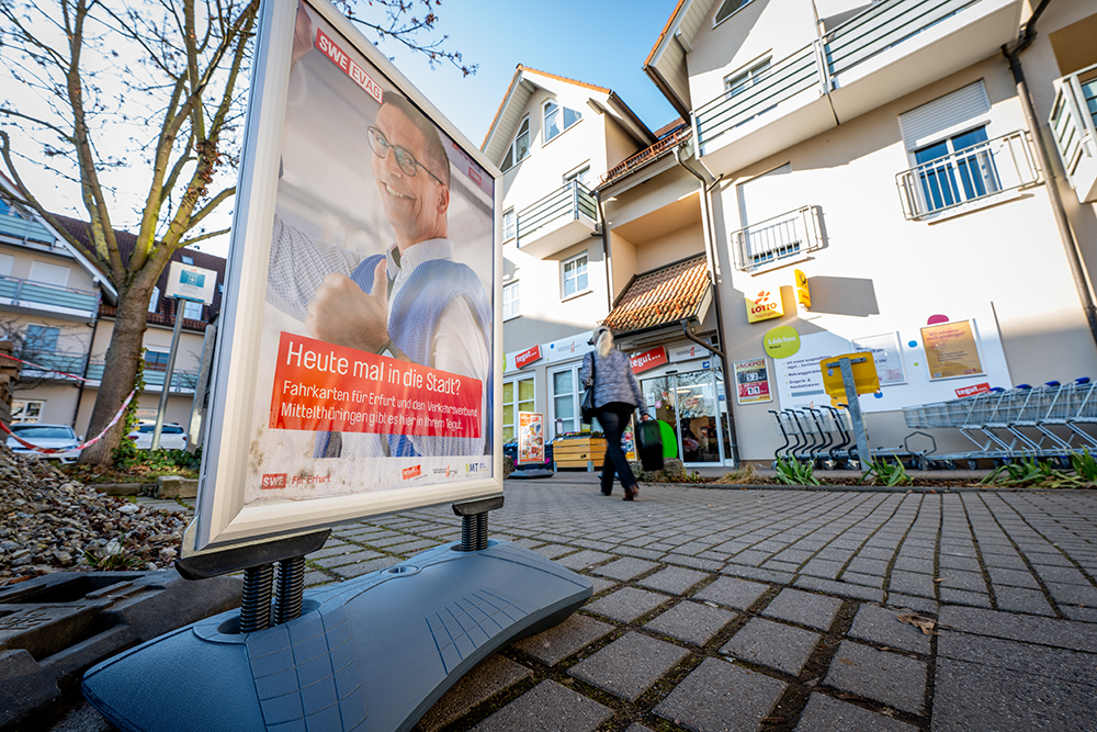 Aufsteller mit EVAG-Werbung vor Ladeneingang.