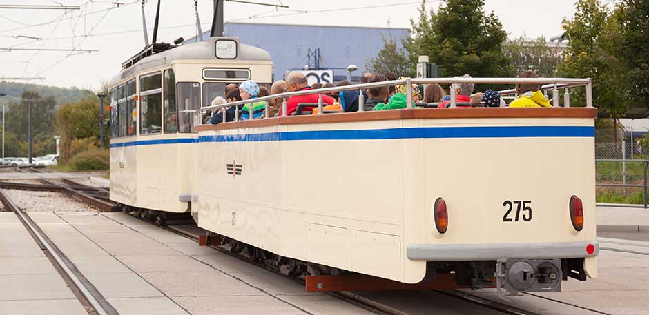 Historischer Cabriowagen Nummer 275  in beiger Lackierung mit blauem Streifen auf dem Betriebshof. Im Wagen sitzen Fahrg&auml;ste.