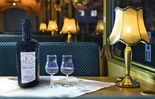 Tisch in einer Stra&szlig;enbahn auf dem eine Flasche Gin und zwei Gl&auml;ser stehen.