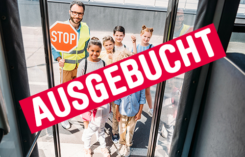 Kinder stehen mit Schülerlotsen vor dem Eingang eines Busses.