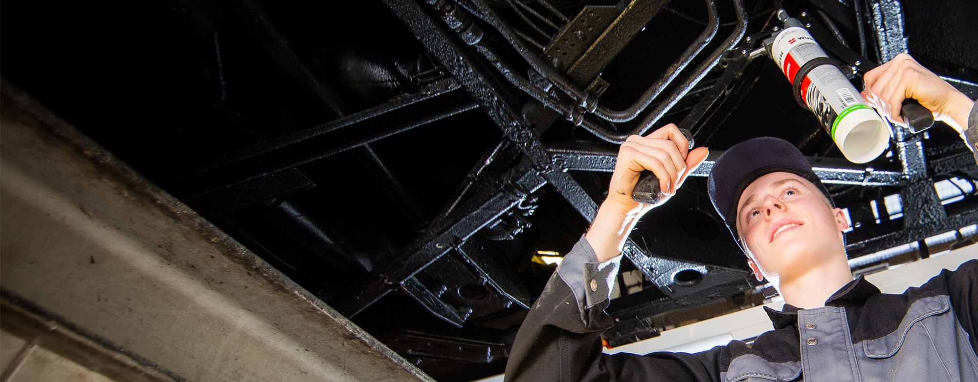 Junger Mann in Arbeitsgruppe unter einem Bus.