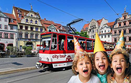 Tatra-Bahn vor historischer Altstadt. Kinder mit Partyh&uuml;ten im Vordergrund.